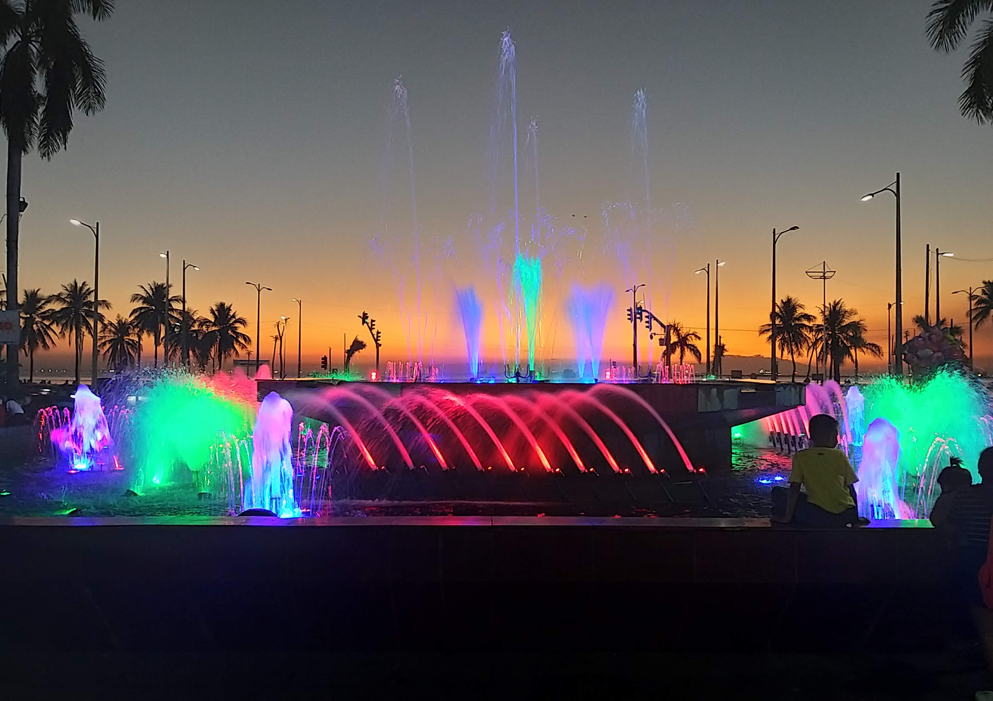 beleuchteter springbrunnen am manila baywalk bei sonnenuntergang
